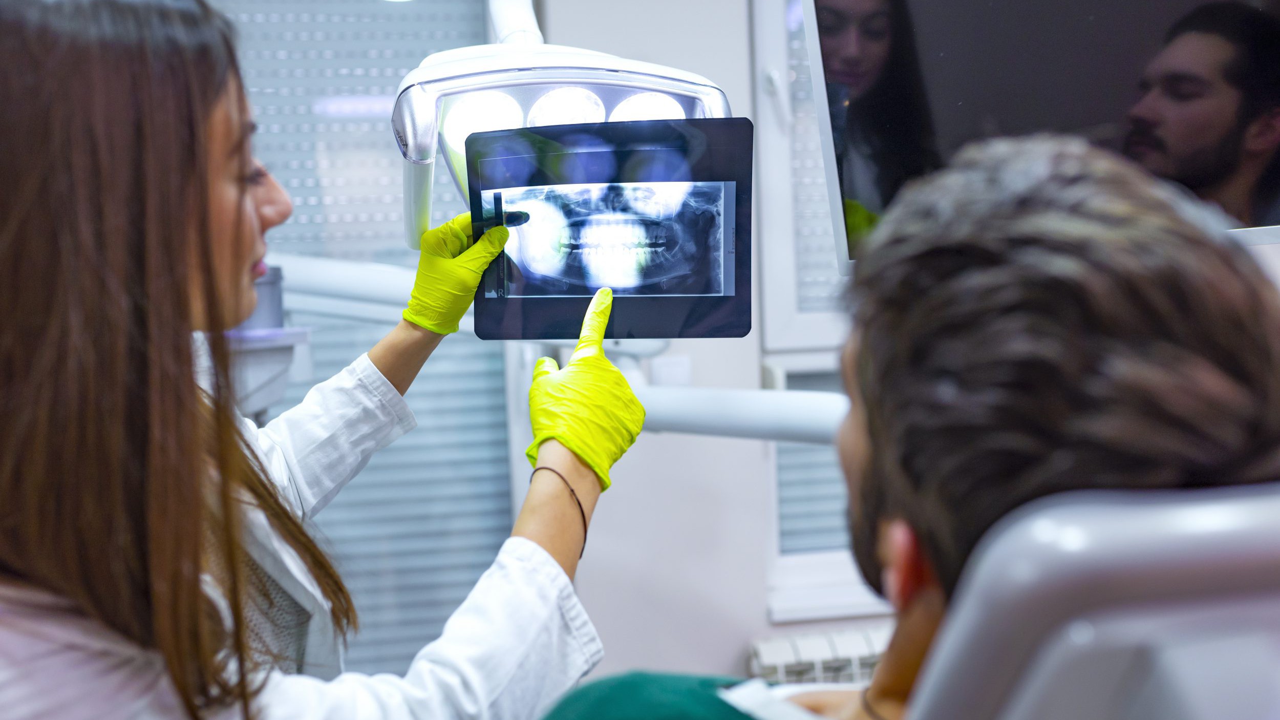 AI dentistry working with Female dentist explaining x-ray image to patient.